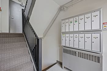 A staircase with a metal railing and a wall of filing cabinets.